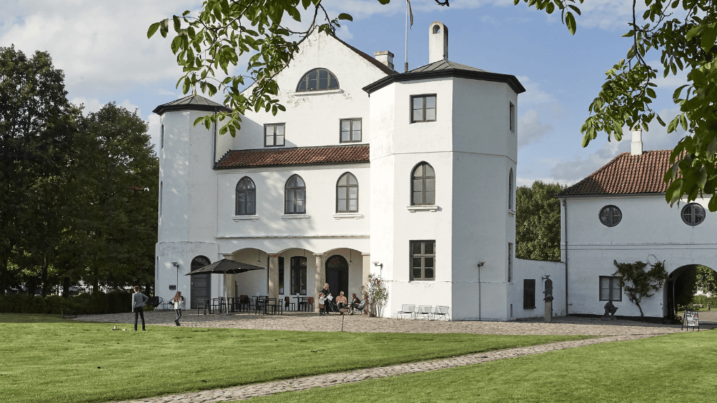 Hvidt slot fotograferet fra slotshaven på en solrig dag